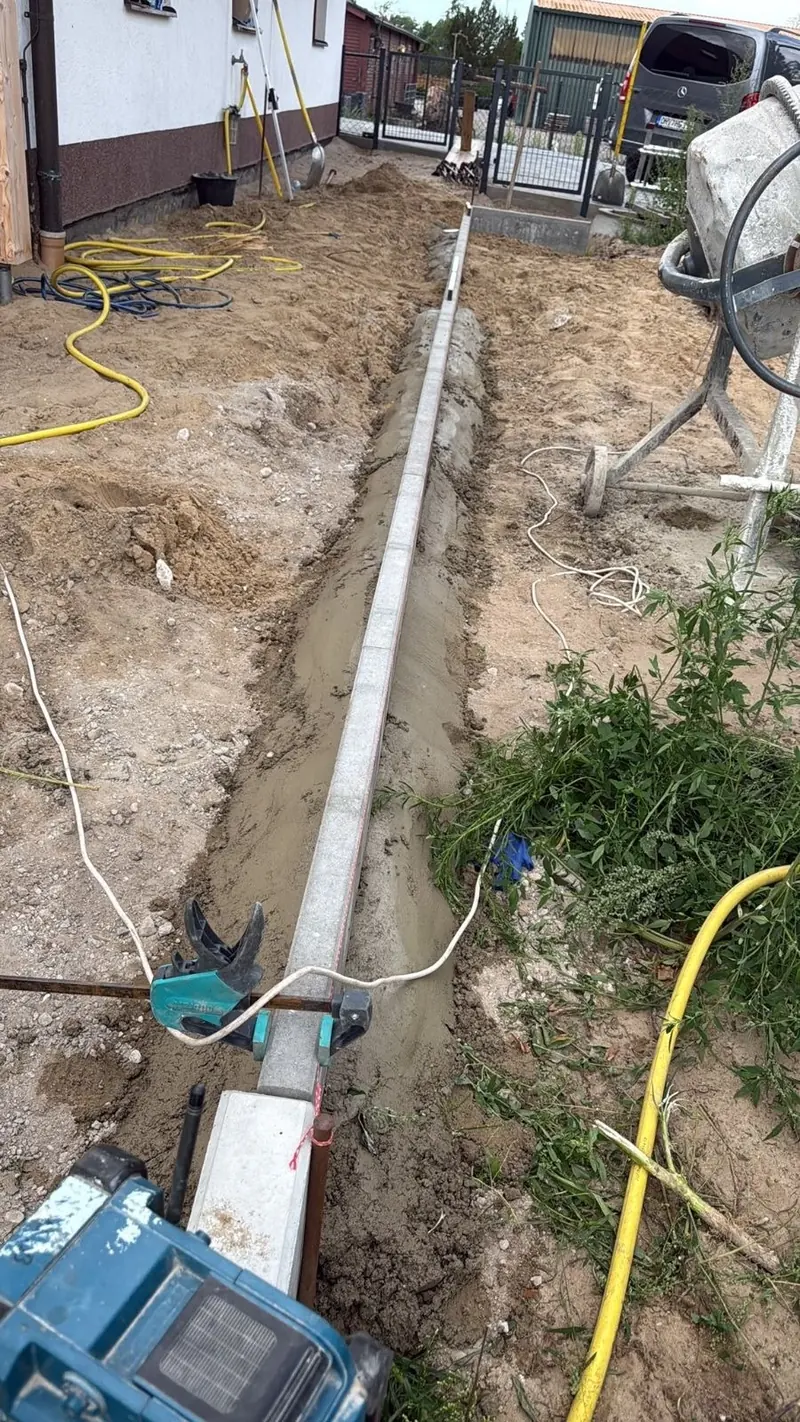 Tiefbordsteine werden nach Richtschnur in Beton gesetzt